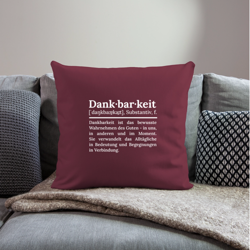 Design-Kissen „Dankfabrik“ in rot auf dem Sofa, hochwertiges Dekokissen mit Botschaft von Dankfabrik.